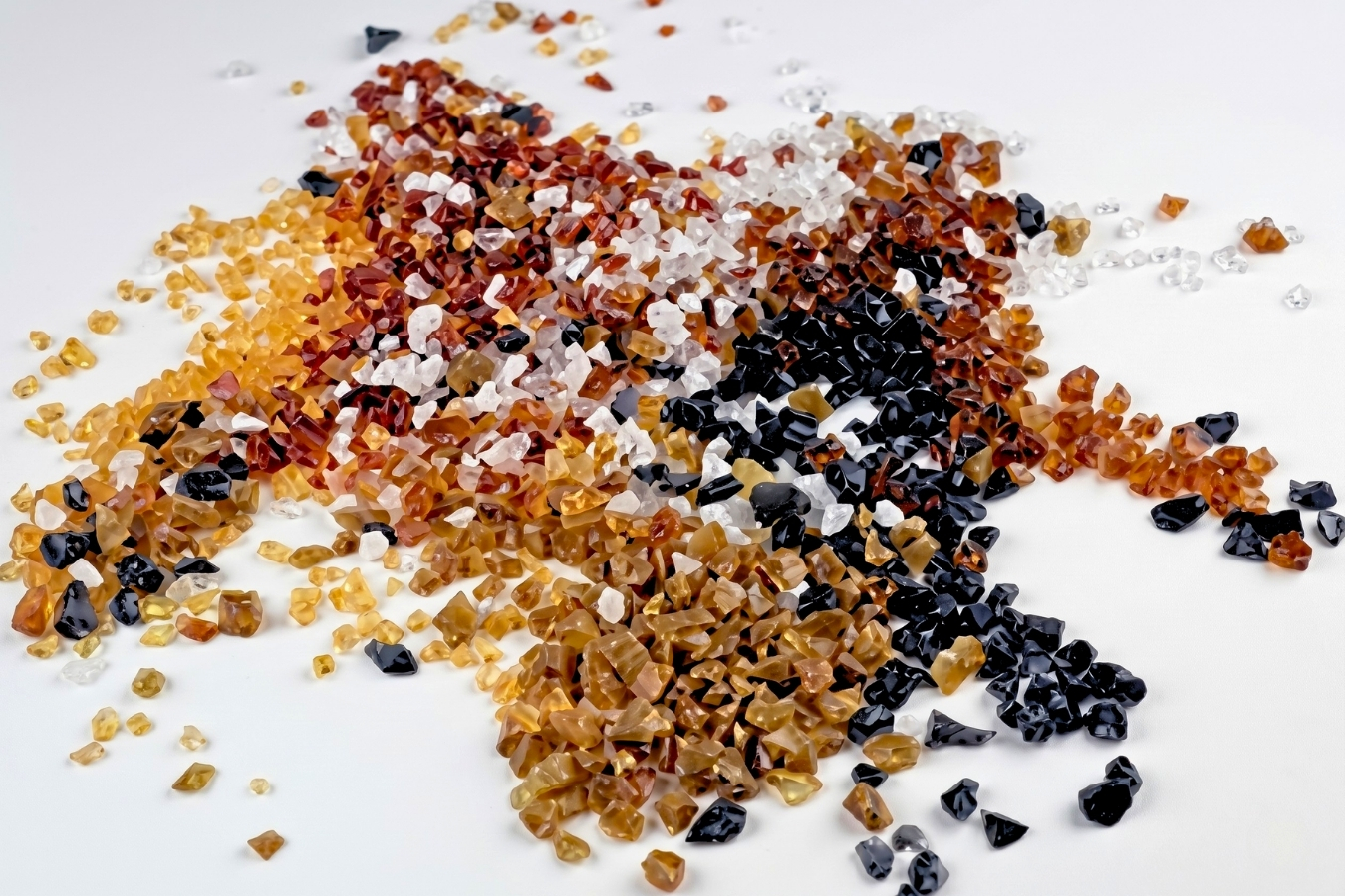 A scattered collection of Marktec decorative chips in amber, terracotta, black, and translucent white; premium stone aggregates for custom solid surface countertop manufacturing and design.