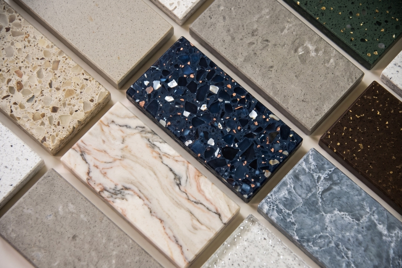 A premium collection of solid surface and quartz countertop samples, including midnight blue terrazzo, veined marble, and emerald green stone; showcasing Marktec’s custom decorative chips and color-matched adhesive capabilities.