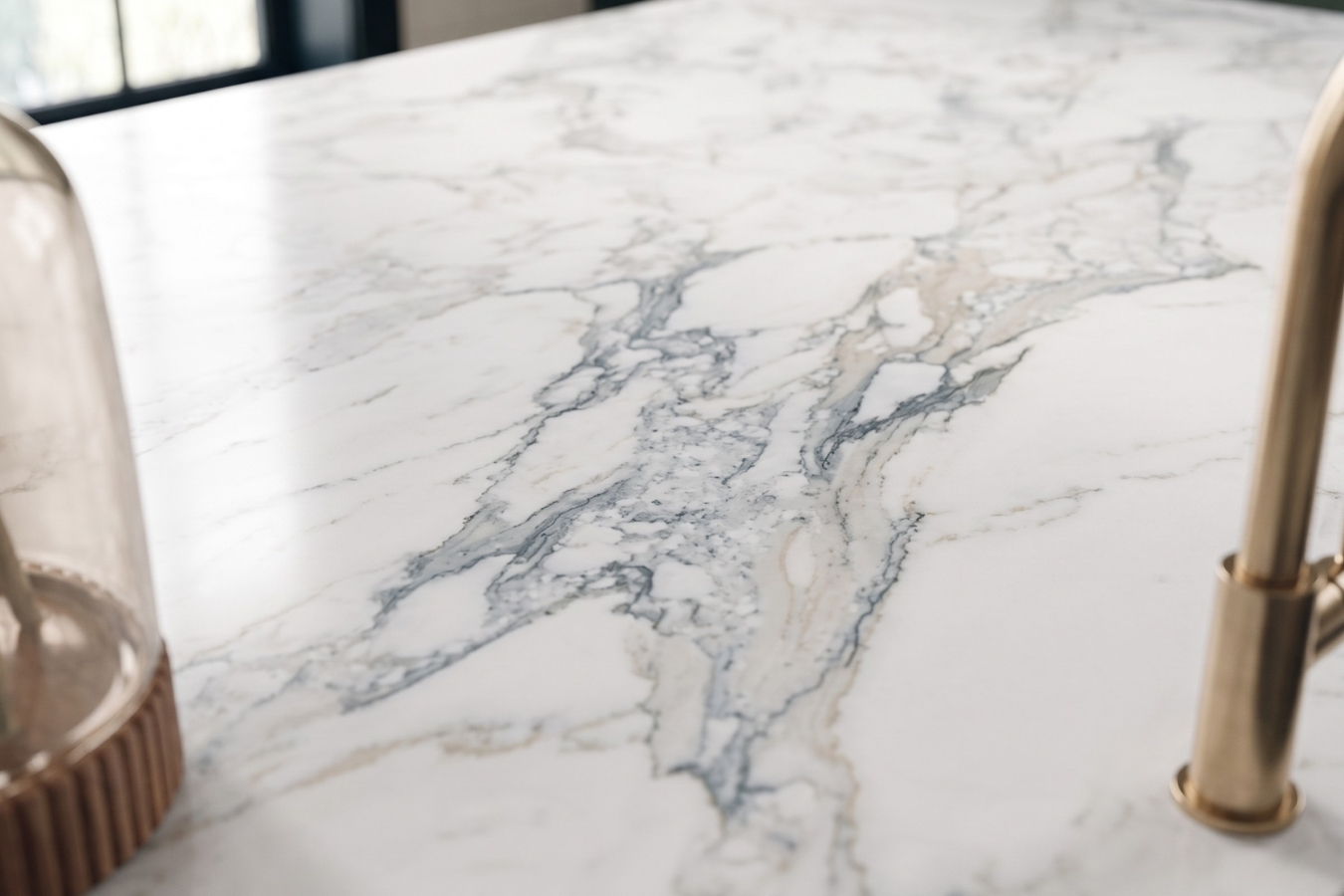 Close-up of premium, heavily veined white marble countertop in a luxury kitchen; seamless mitered edge fabrication and precise color-matching bonding achieved using Marktec specialized stone adhesives.