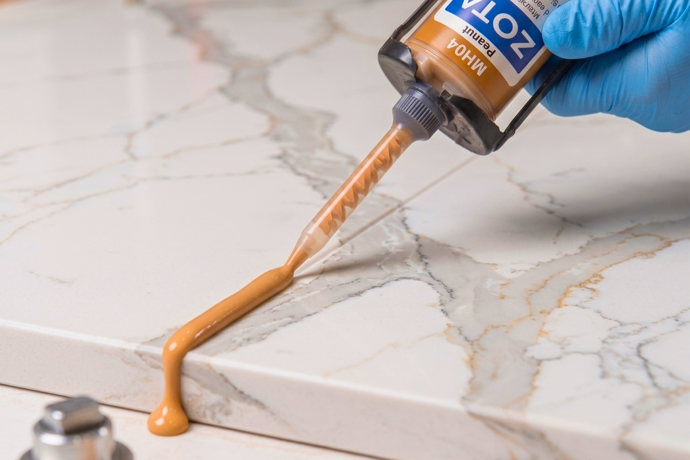 Applying ZOTA MH04 Peanut adhesive to a quartz countertop; Marktec color-matched glue being dispensed through a mixing nozzle for seamless stone jointing.